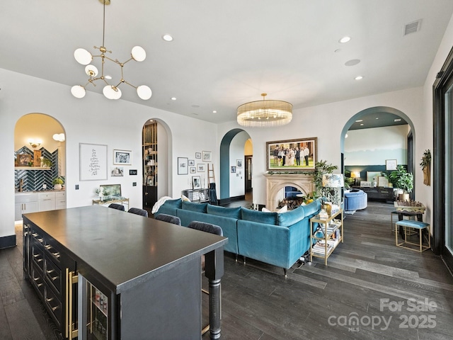 interior space featuring a center island, pendant lighting, a notable chandelier, and dark wood-type flooring