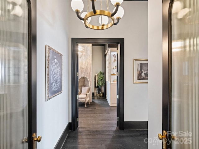 corridor featuring dark hardwood / wood-style floors and an inviting chandelier