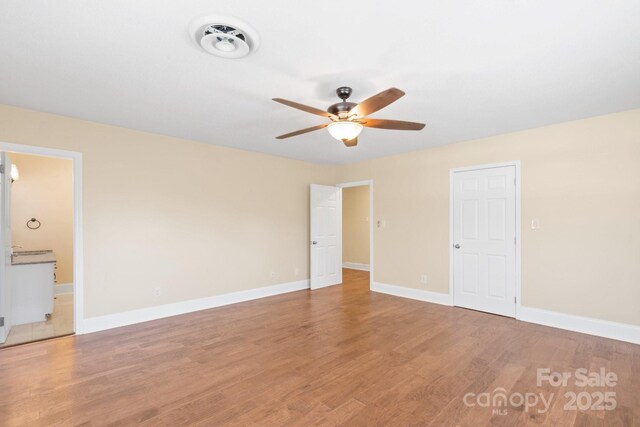 unfurnished bedroom featuring connected bathroom, hardwood / wood-style floors, and ceiling fan