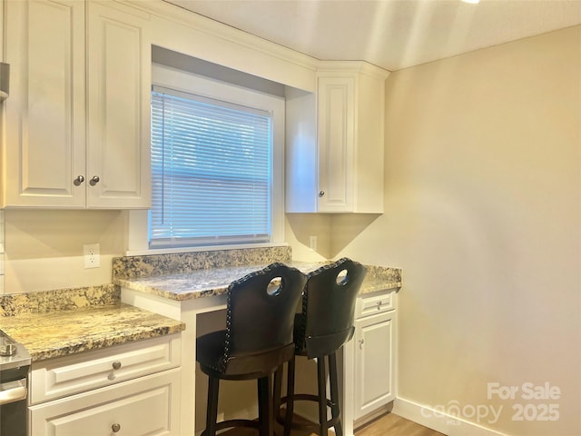 kitchen with light stone counters, built in study area, and white cabinetry