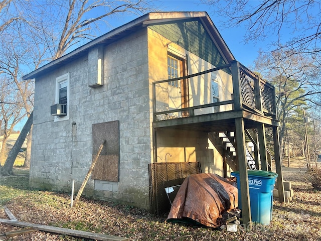 view of side of property with stairway, concrete block siding, and a deck