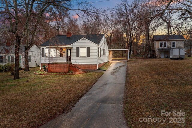 view of front of house with a detached carport, driveway, a chimney, and a front lawn