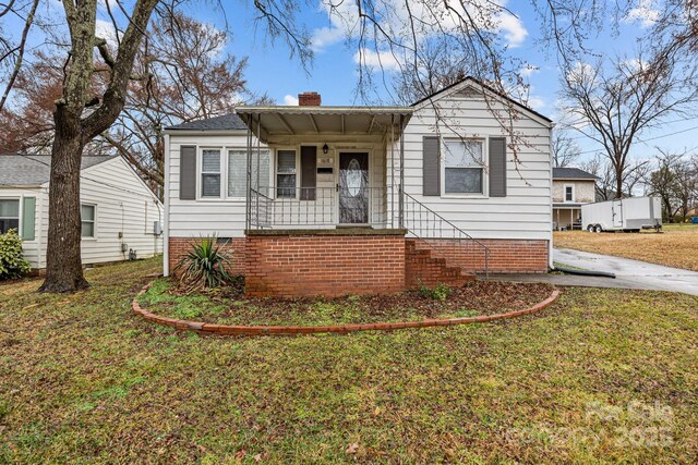 bungalow-style house with covered porch, crawl space, a front lawn, and a chimney