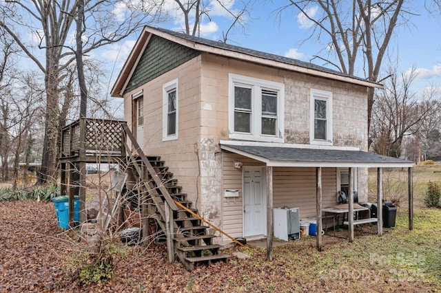 exterior space featuring a shingled roof and stairway