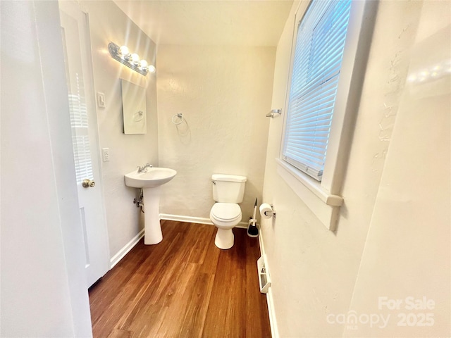 bathroom featuring toilet, a sink, baseboards, and wood finished floors