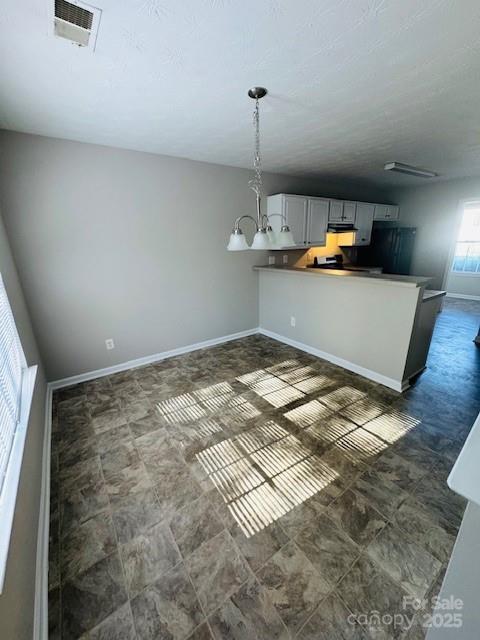 kitchen with hanging light fixtures, gray cabinets, a notable chandelier, and kitchen peninsula