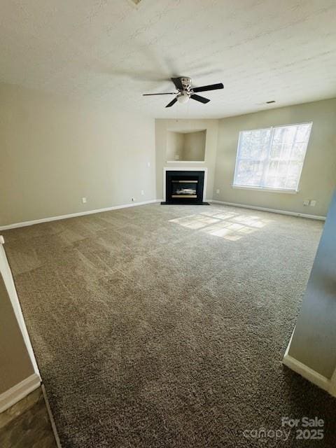 unfurnished living room featuring ceiling fan, a textured ceiling, and dark carpet