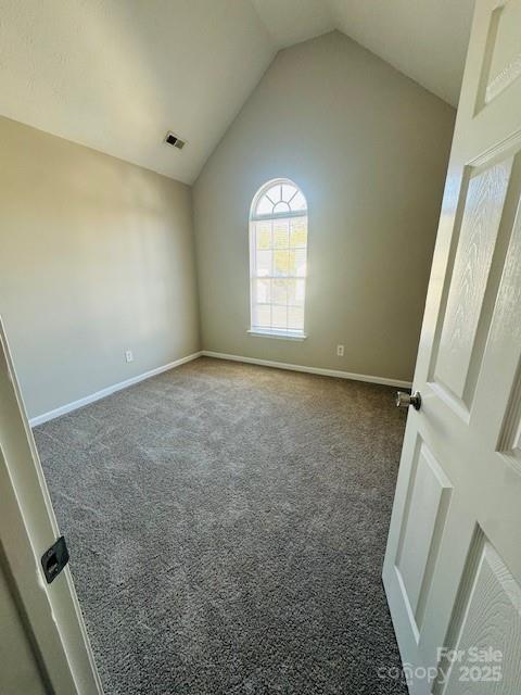 carpeted empty room featuring vaulted ceiling