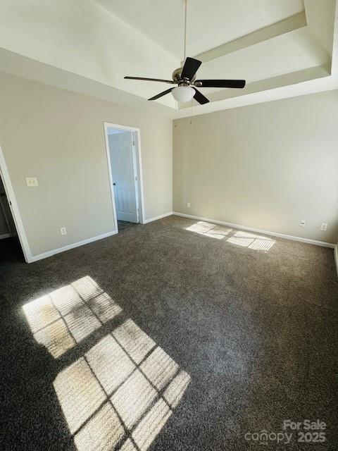 carpeted spare room with a raised ceiling and ceiling fan