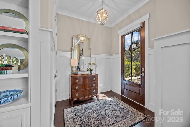 foyer with dark hardwood / wood-style flooring, ornamental molding, and a chandelier