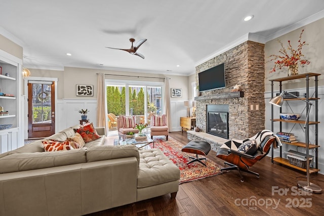 living room featuring ceiling fan, crown molding, a fireplace, and wood-type flooring