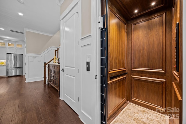 details featuring stainless steel refrigerator, elevator, ornamental molding, and hardwood / wood-style flooring