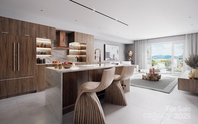 kitchen with backsplash, a kitchen bar, a center island, a mountain view, and wall chimney exhaust hood