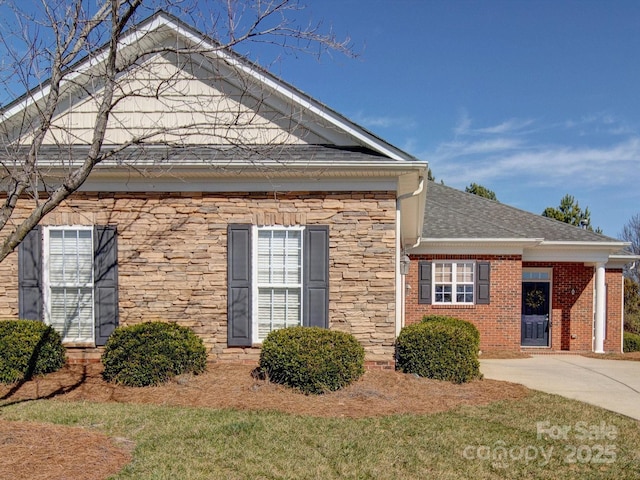 view of home's exterior featuring brick siding, stone siding, and roof with shingles