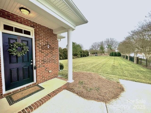 entrance to property with a yard and brick siding