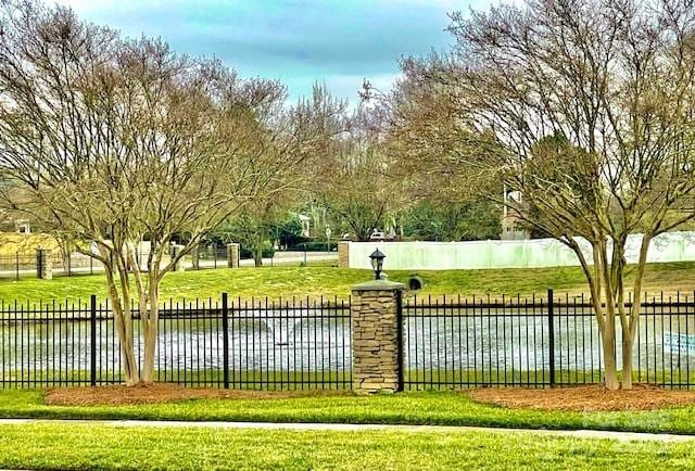 view of home's community featuring fence, a water view, and a lawn