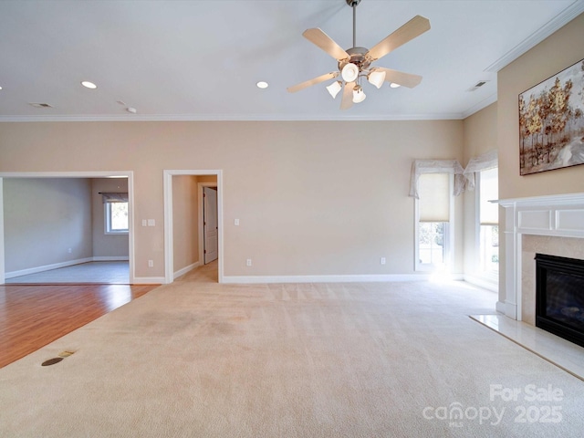 unfurnished living room featuring crown molding, light colored carpet, ceiling fan, and a high end fireplace