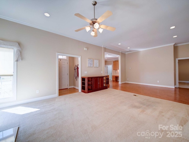 unfurnished living room featuring crown molding, carpet floors, and ceiling fan