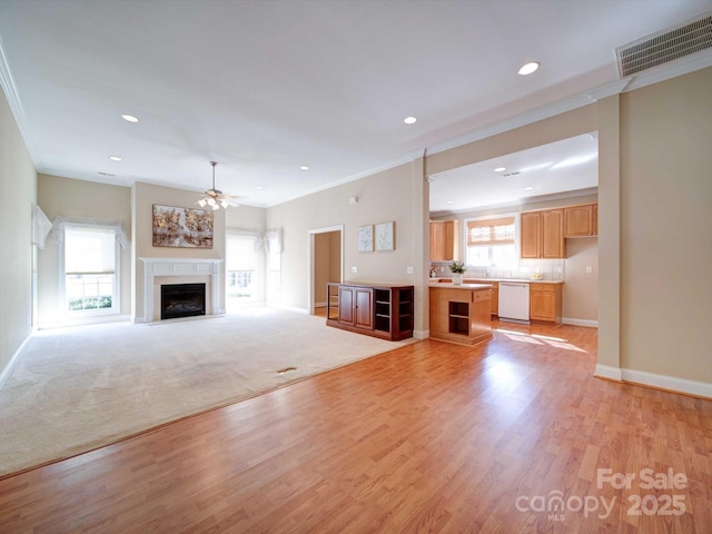 unfurnished living room featuring visible vents, a fireplace with flush hearth, light wood-style floors, crown molding, and baseboards