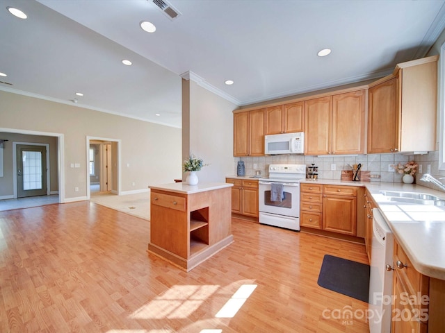 kitchen featuring sink, light hardwood / wood-style flooring, a kitchen island, white appliances, and decorative backsplash