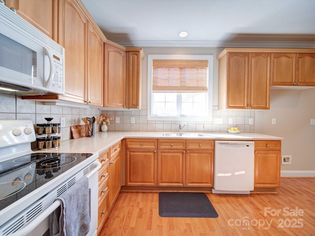 kitchen featuring white appliances, light countertops, light wood-type flooring, and a sink