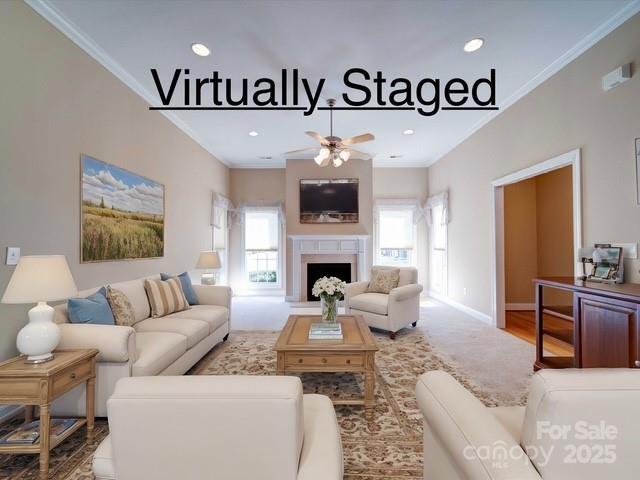 living room featuring a healthy amount of sunlight, a fireplace with raised hearth, and ornamental molding