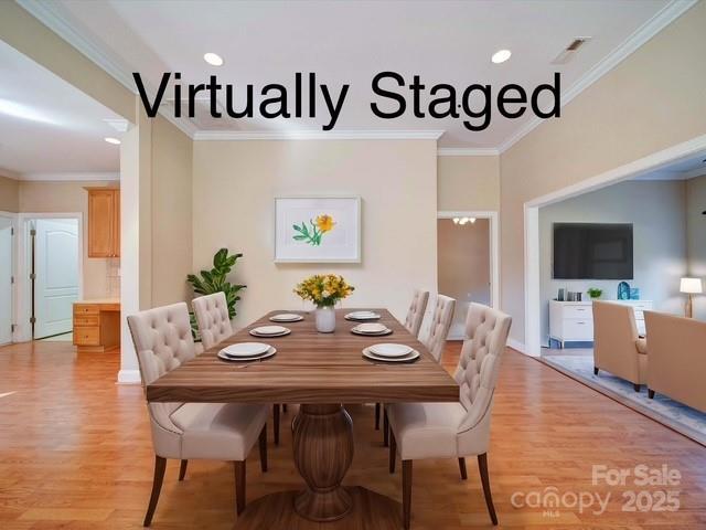 dining space with visible vents, light wood-style flooring, and ornamental molding