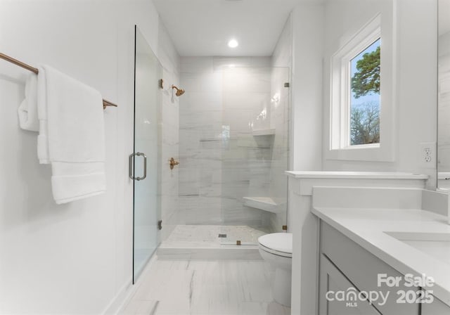 bathroom featuring a shower with door, vanity, and toilet