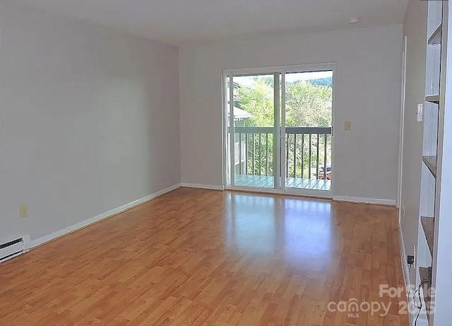 unfurnished room with a baseboard heating unit and light wood-type flooring