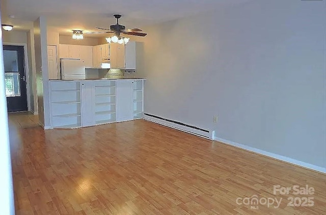 interior space featuring ceiling fan, baseboard heating, white refrigerator, white cabinets, and light wood-type flooring