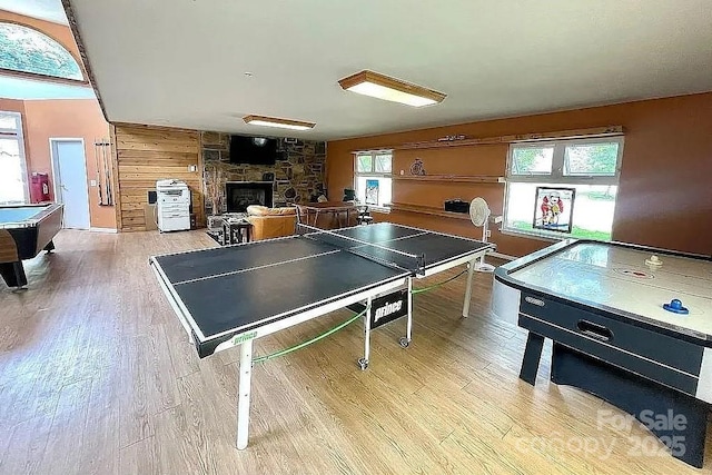 recreation room with a stone fireplace and light wood-type flooring