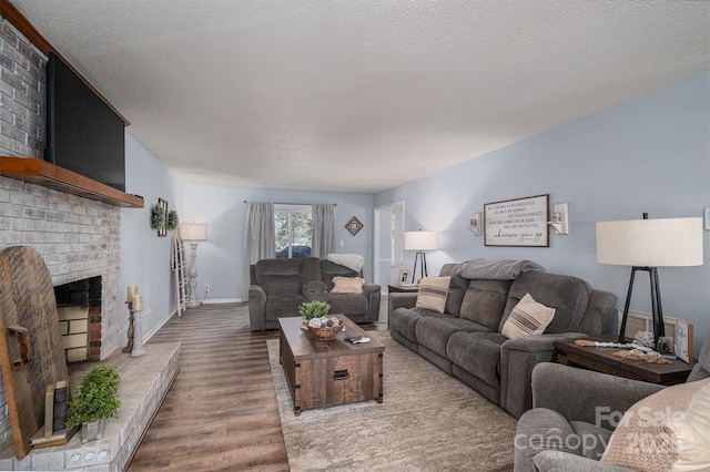 living room with hardwood / wood-style floors, a fireplace, and a textured ceiling