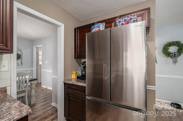 kitchen featuring stainless steel fridge, dark hardwood / wood-style floors, and a textured ceiling