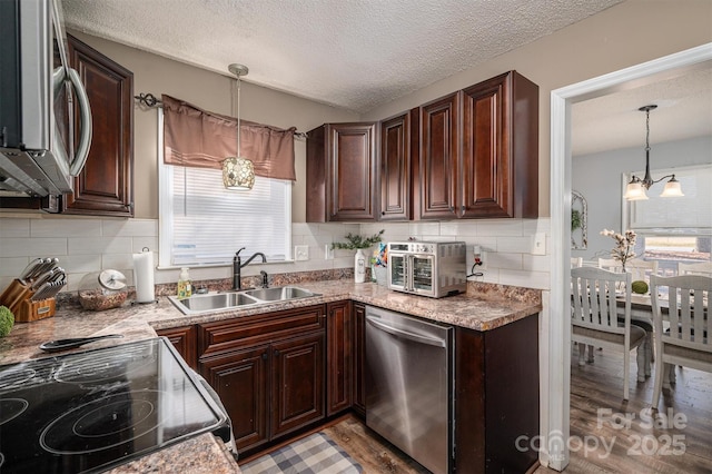 kitchen featuring tasteful backsplash, sink, hardwood / wood-style flooring, hanging light fixtures, and stainless steel appliances