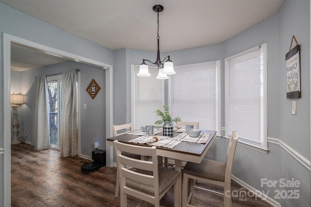 dining area with dark hardwood / wood-style flooring, a notable chandelier, and a textured ceiling