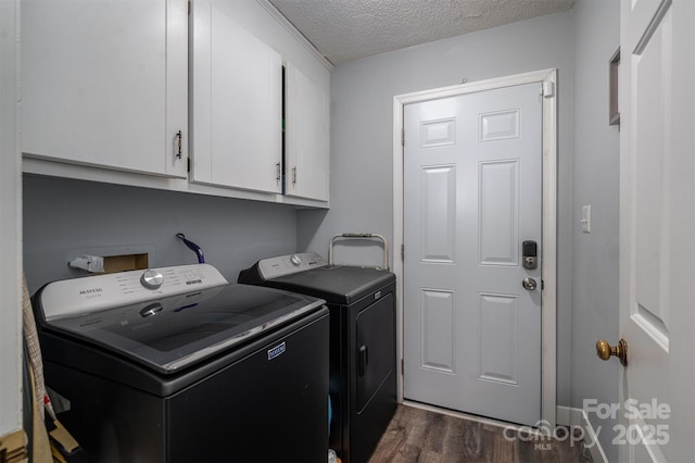 laundry area featuring dark wood-type flooring, washer and clothes dryer, cabinets, and a textured ceiling