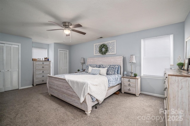 carpeted bedroom featuring multiple closets, ceiling fan, and a textured ceiling