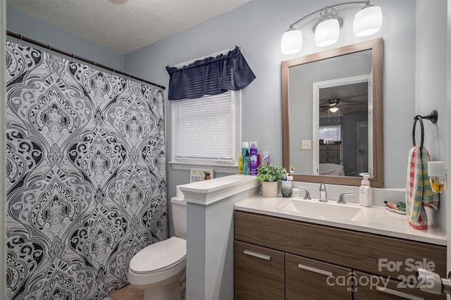 bathroom with vanity, toilet, and a textured ceiling