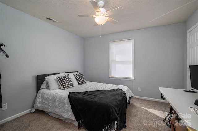 carpeted bedroom featuring ceiling fan and a textured ceiling