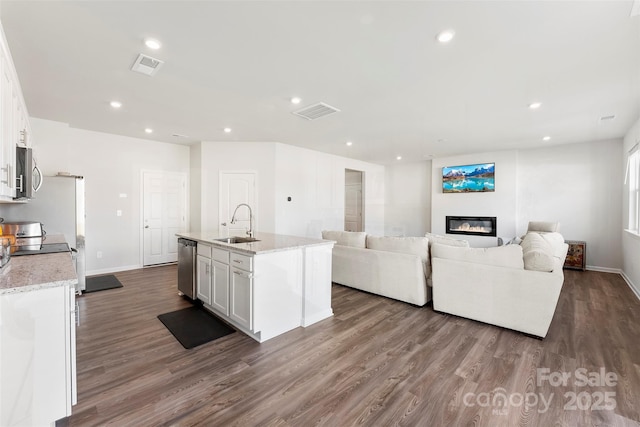 kitchen with white cabinetry, light stone countertops, a kitchen island with sink, and stainless steel appliances