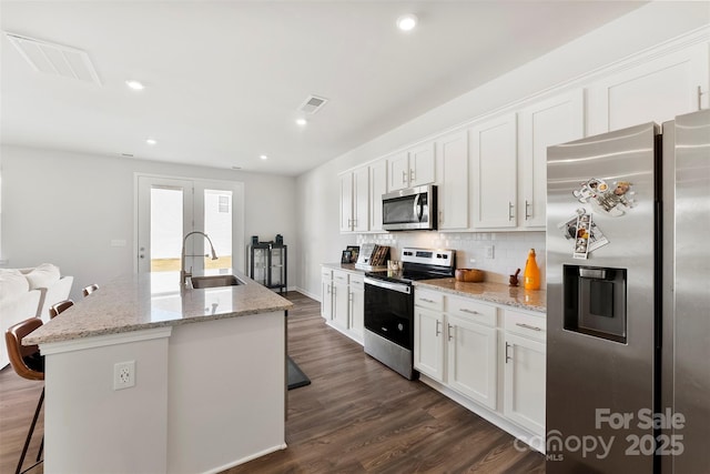 kitchen with sink, white cabinets, a kitchen breakfast bar, a kitchen island with sink, and stainless steel appliances