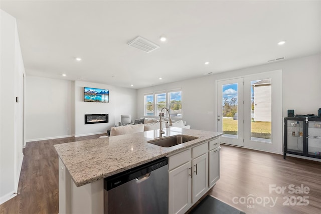 kitchen featuring sink, white cabinetry, light stone counters, a center island with sink, and stainless steel dishwasher