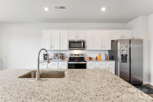 kitchen featuring light stone counters, stainless steel appliances, sink, and white cabinets