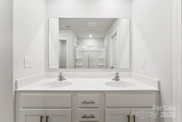 bathroom featuring a shower with door and vanity