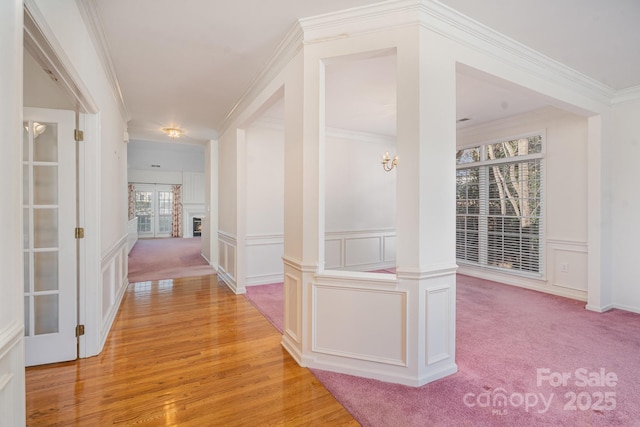 hall featuring ornamental molding, light colored carpet, and decorative columns