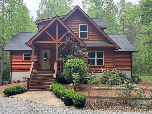 log home with central AC, log exterior, and a shingled roof