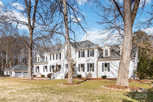 colonial-style house featuring a garage, an outdoor structure, and a front lawn