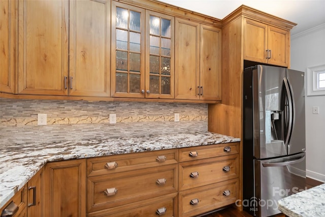 kitchen featuring crown molding, decorative backsplash, stainless steel fridge, and light stone countertops