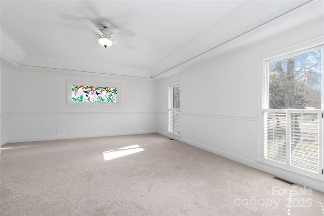 carpeted empty room with ceiling fan and a tray ceiling