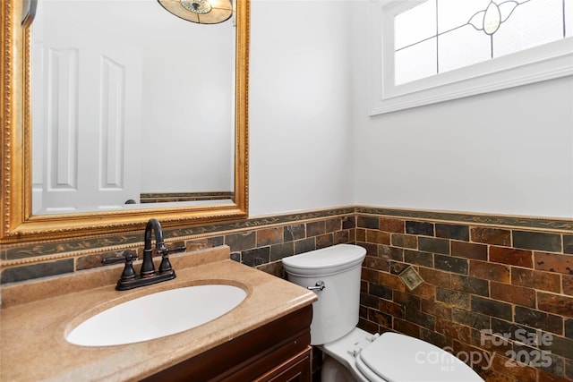 bathroom featuring vanity, tile walls, and toilet